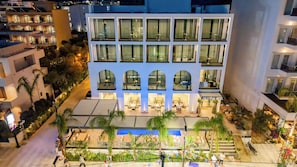 A hotel with multiple floors, outdoor seating areas, and a sign indicating the hotel name.