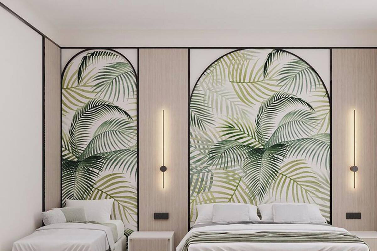 A hotel room with a large bed, two bedside tables, and a wall with a tropical leaf pattern.