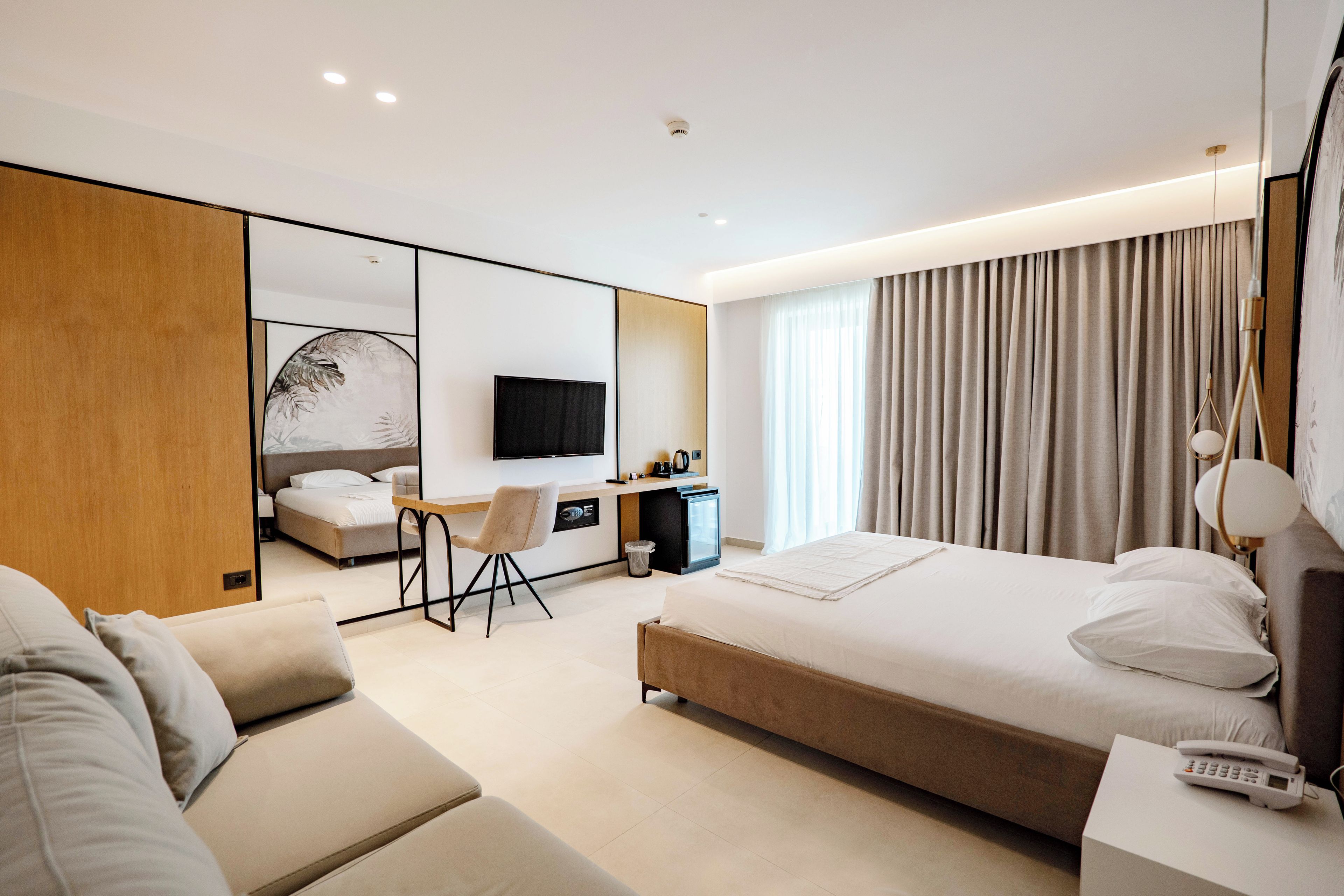 Een moderne hotelkamer met een groot bed, een bureau, een bank en een televisie.