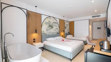 A modern hotel room with a large bathtub, two beds, a seating area, and a flat-screen TV.