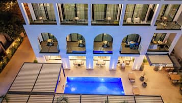A hotel with multiple balconies, a central pool, and outdoor seating areas.