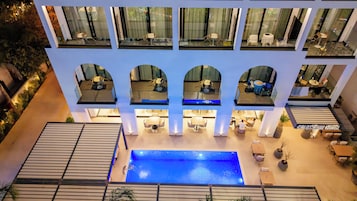 A hotel with multiple balconies, a central pool, and outdoor seating areas.