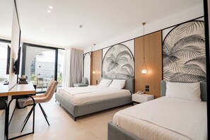 A modern hotel room with two beds, a desk, a chair, and a large window. - Hotel Colosseum (Ksamil)