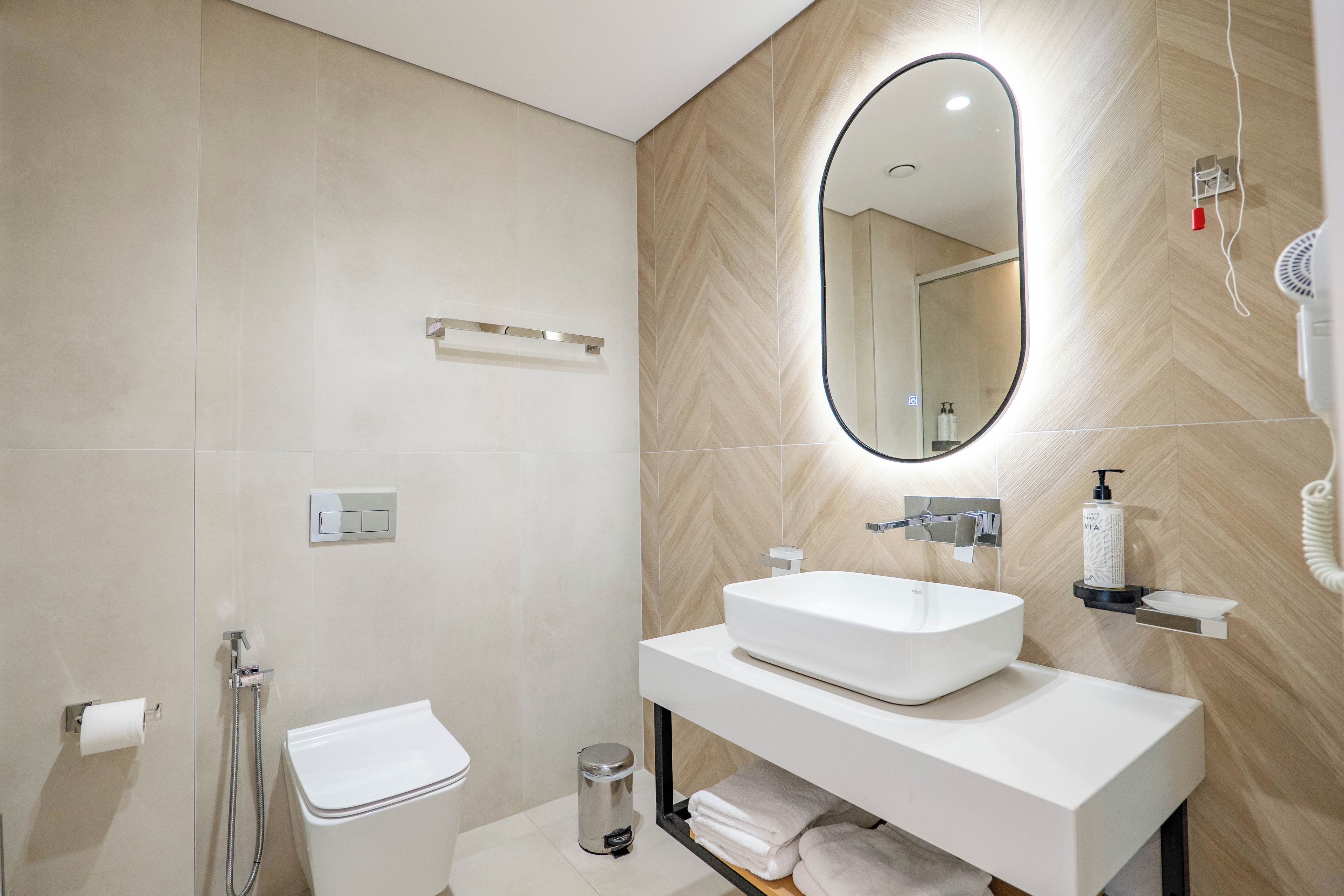 A modern bathroom with a white sink, mirror, and toilet.