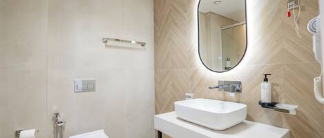 A modern bathroom with a white sink, mirror, and toilet.