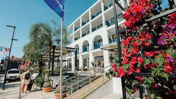 Un hotel con un diseño arquitectónico moderno, destacando una escalera prominente que conduce a la entrada, y una bandera que indica un evento o promoción especial.