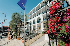 A hotel with a modern architectural design, featuring a prominent staircase leading to the entrance, and a flag indicating a special event or promotion.