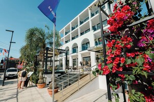 Un hôtel doté d’une architecture moderne, avec un escalier imposant menant à l’entrée et un drapeau signalant un événement spécial ou une promotion.