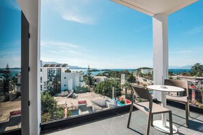A balcony with a view of a coastal town, a pool, and a table with chairs. - Hotel Colosseum (Ksamil)