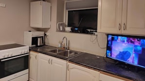 Una cocina con estufa, horno, pileta y una ventana sobre la encimera.