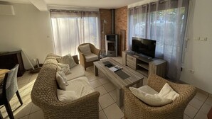 A living room with a sofa set, a coffee table, a TV, and a fireplace. - Spacious villa with veranda and garden in Capbreton (Capbreton)