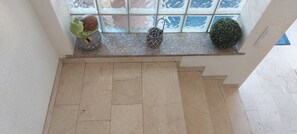A marble staircase leading to a balcony with decorative items including a frog, a snail, and a basket.