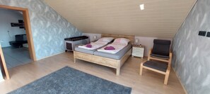 A bedroom with a sloped ceiling, a bed with a headboard, a bedside table, a chair, and a rug.