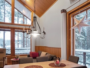 A cozy cabin interior with a wooden ceiling, large windows, a dining table, and a star decoration. - Lomahokkila by Interhome (Sotkamo)