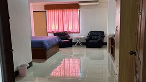Una habitación con una cama, dos sillas, una mesita y un armario.