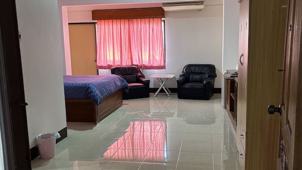 Una habitación con una cama, dos sillas, una mesita y un armario.