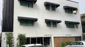 Un edificio de dos pisos con varias ventanas, una puerta de garaje y un coche estacionado al frente.