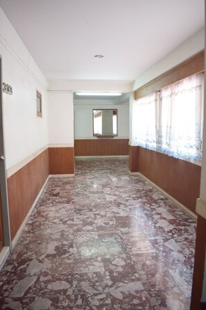 A hallway with a marble floor, wooden paneling on the walls, and a window with a curtain. -  My Hotel Bangkok Noi (Bangkok)