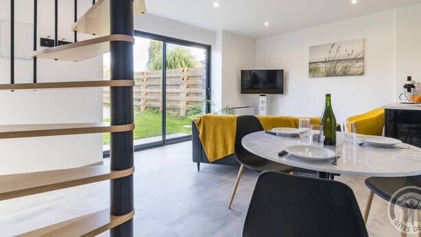 Ein moderner Essbereich mit einem runden Tisch, Stühlen und einem Fernseher an der Wand.