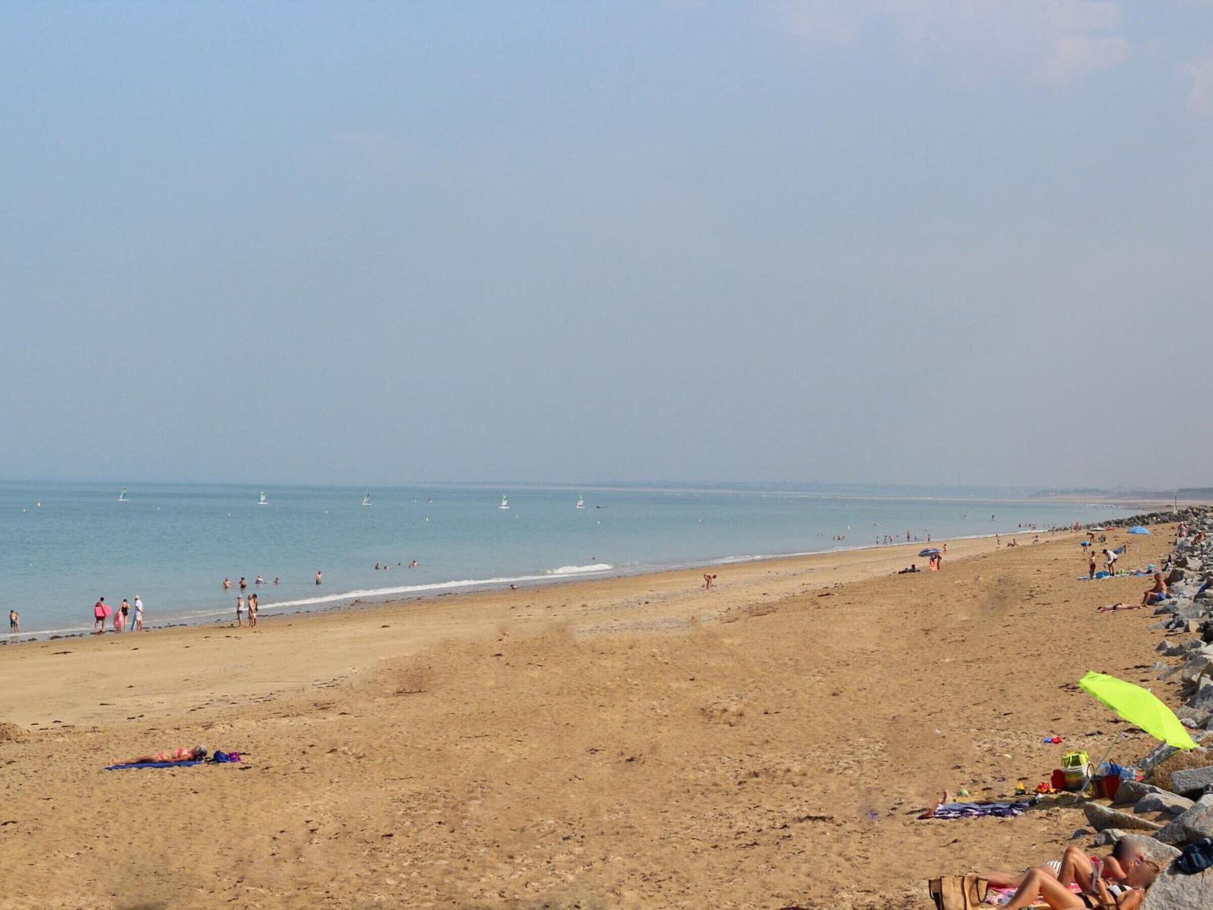 Une vaste plage de sable fin, avec un ciel dégagé et une mer calme.