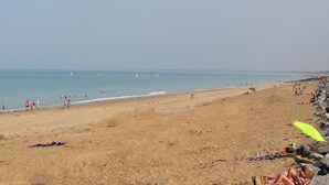 Ein weiter, sandiger Strand mit blauem Himmel und ruhiger See.