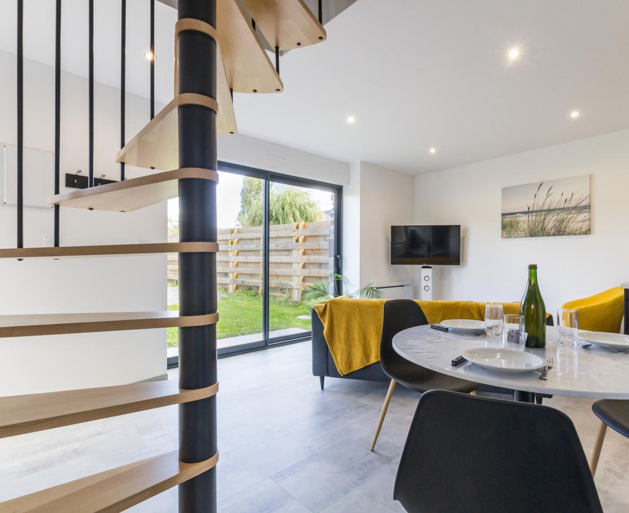 Un espace repas moderne avec une table ronde, des chaises et un téléviseur fixé au mur.