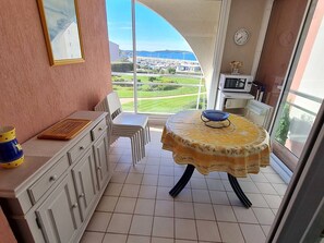Enjoy a tranquil view of the marina from this cozy room, featuring a dining table and a comfortable chair.