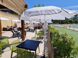 Enjoy a leisurely meal in our outdoor seating area, surrounded by a well-manicured lawn and a serene pool.