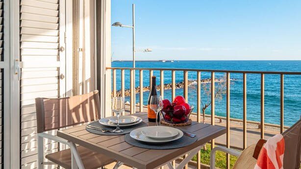 A table set for two on a balcony with a view of the sea. - Modern Apartment Facing Sant Antoni Beach (San Antonio de Calonge)