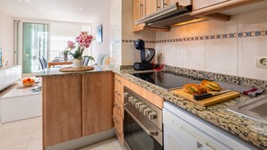 A modern kitchen with a built-in oven, a stovetop, and a coffee maker. - Modern Apartment Facing Sant Antoni Beach (San Antonio de Calonge)