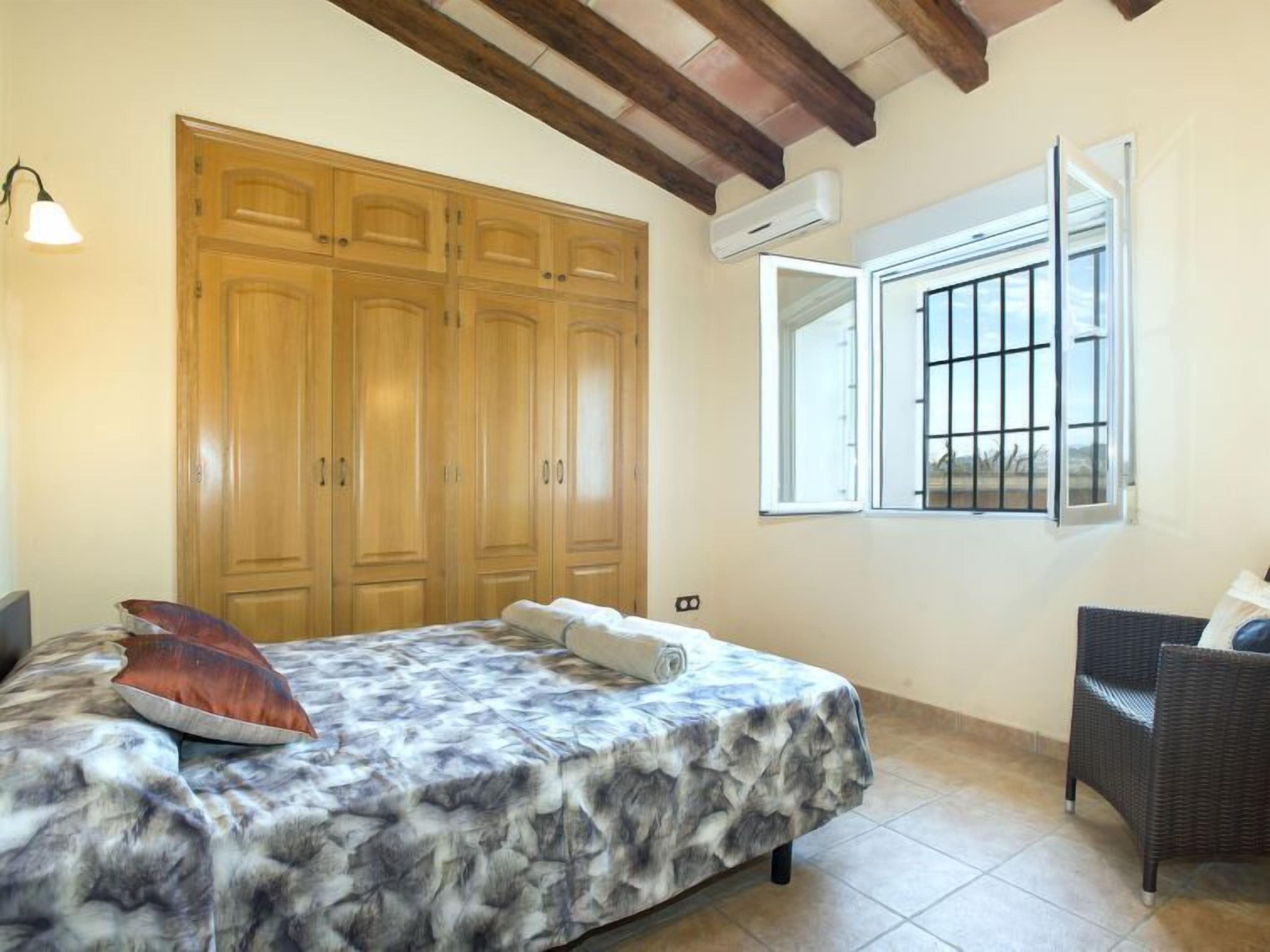 Een slaapkamer met een bed, een kledingkast, een raam en een stoel.