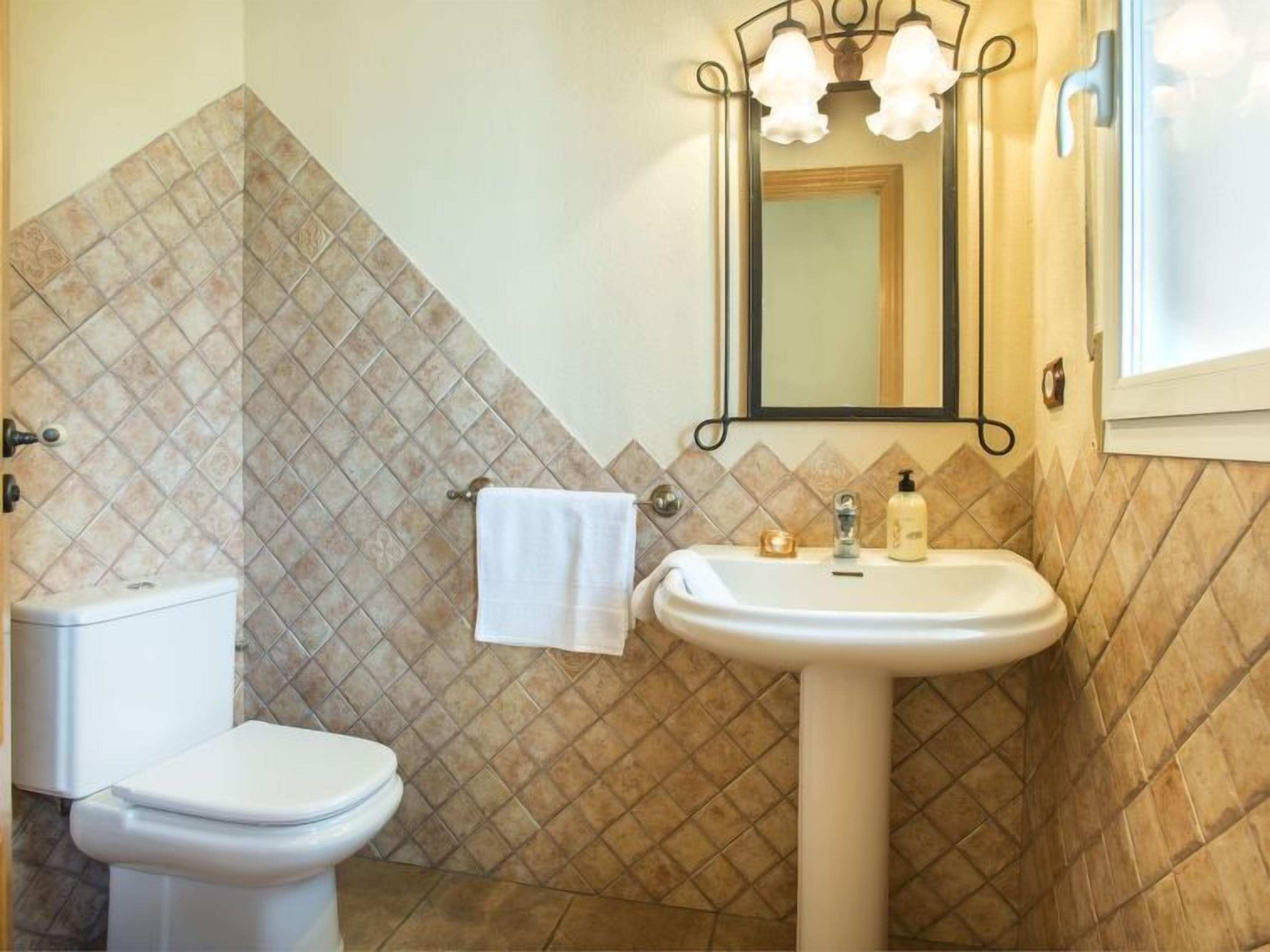 Une salle de bain avec des toilettes, un lavabo et une serviette accrochée au mur.