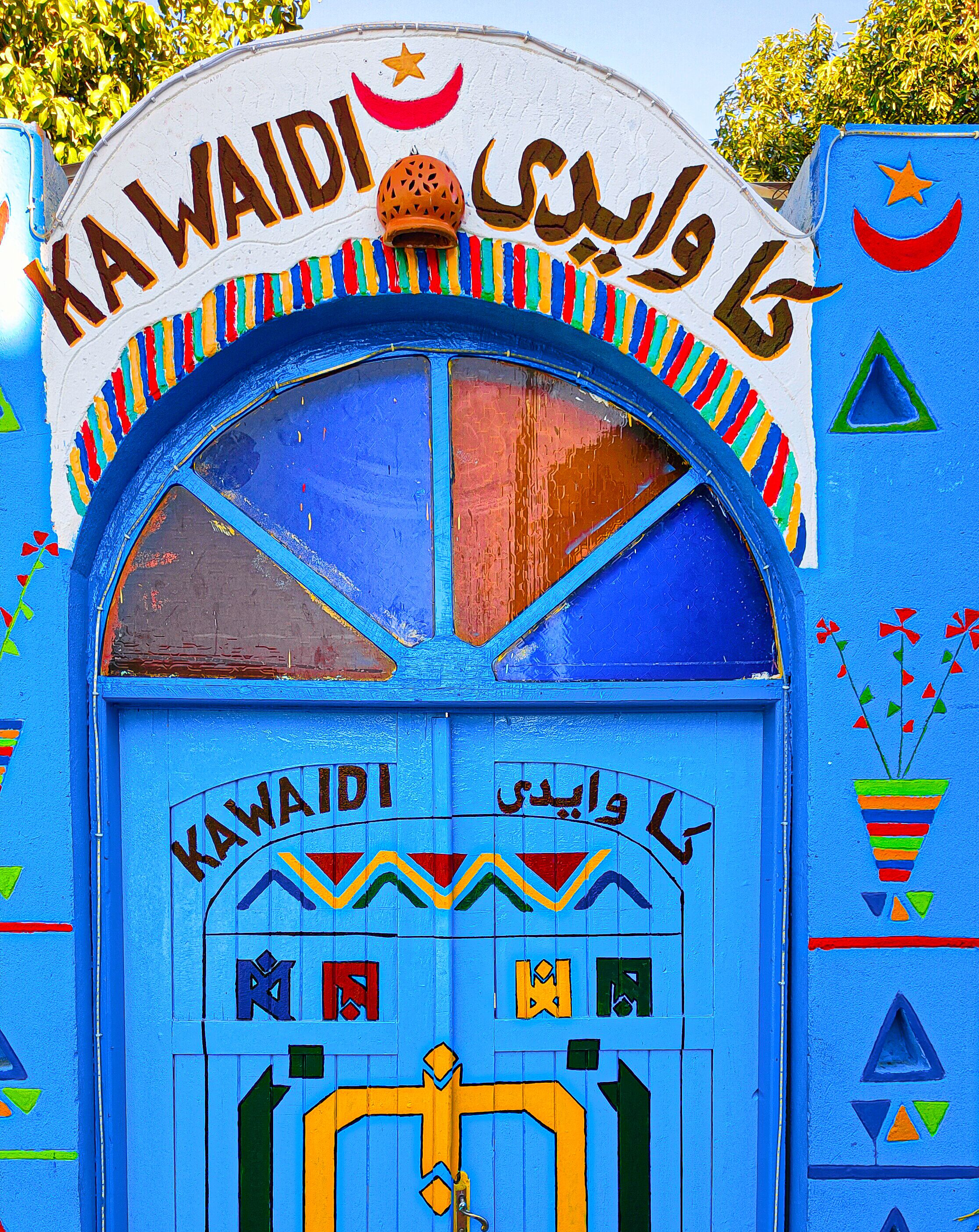 A colorful, traditional gate with Arabic script and geometric patterns.