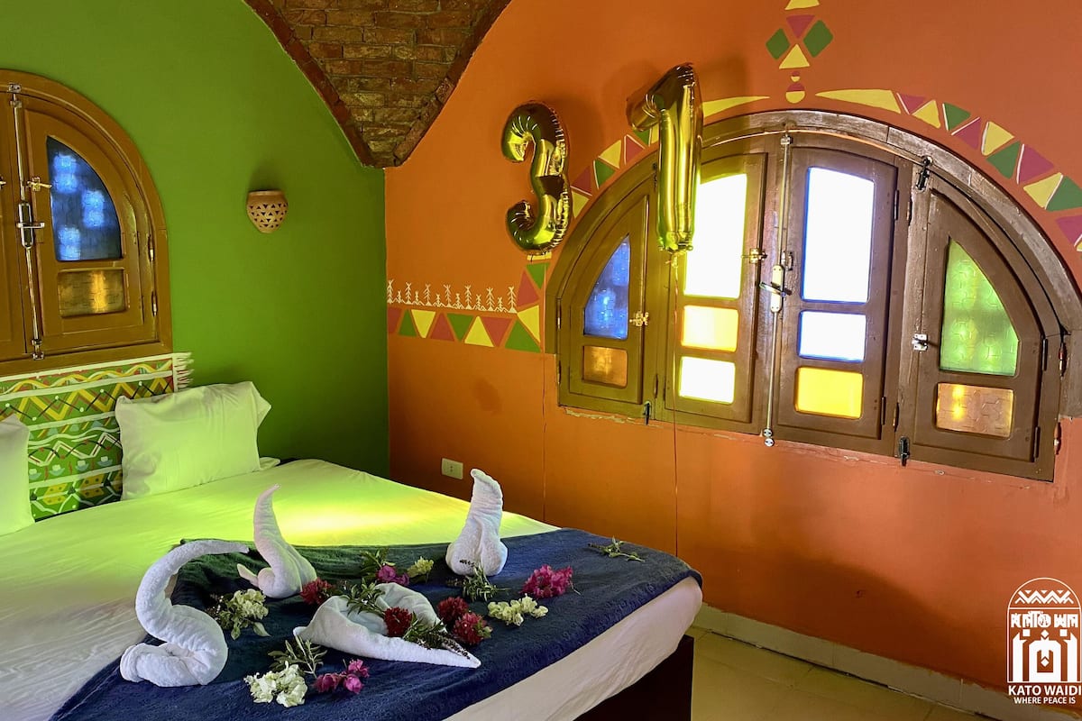 Een hotelkamer met een bed, twee zwanenzacht kussens en een bloemstuk.