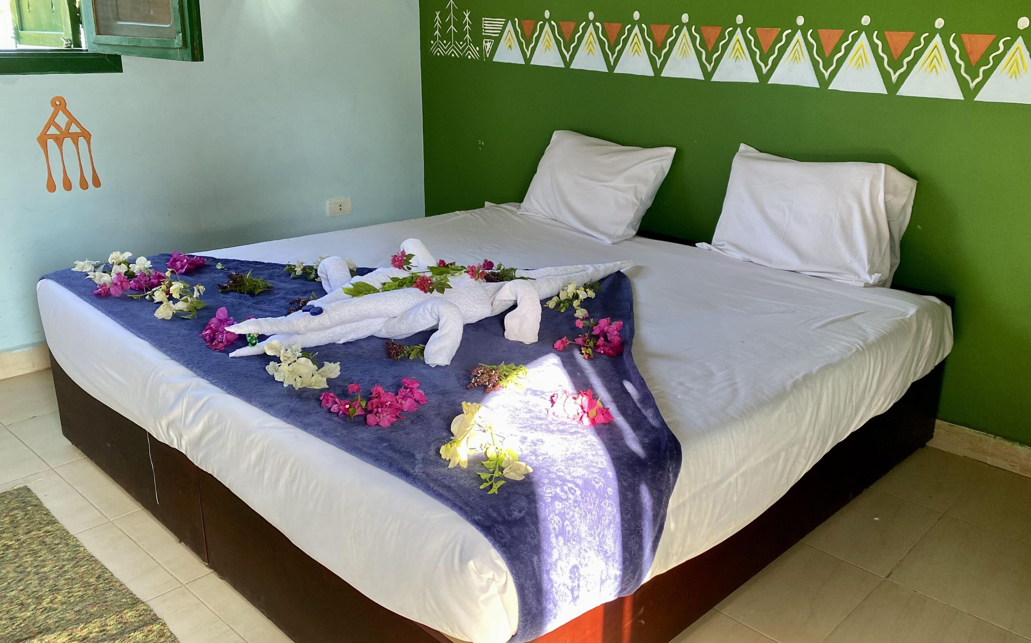 A neatly made bed with a blue and white patterned bedspread, white pillows, and a decorative headboard with a geometric design.