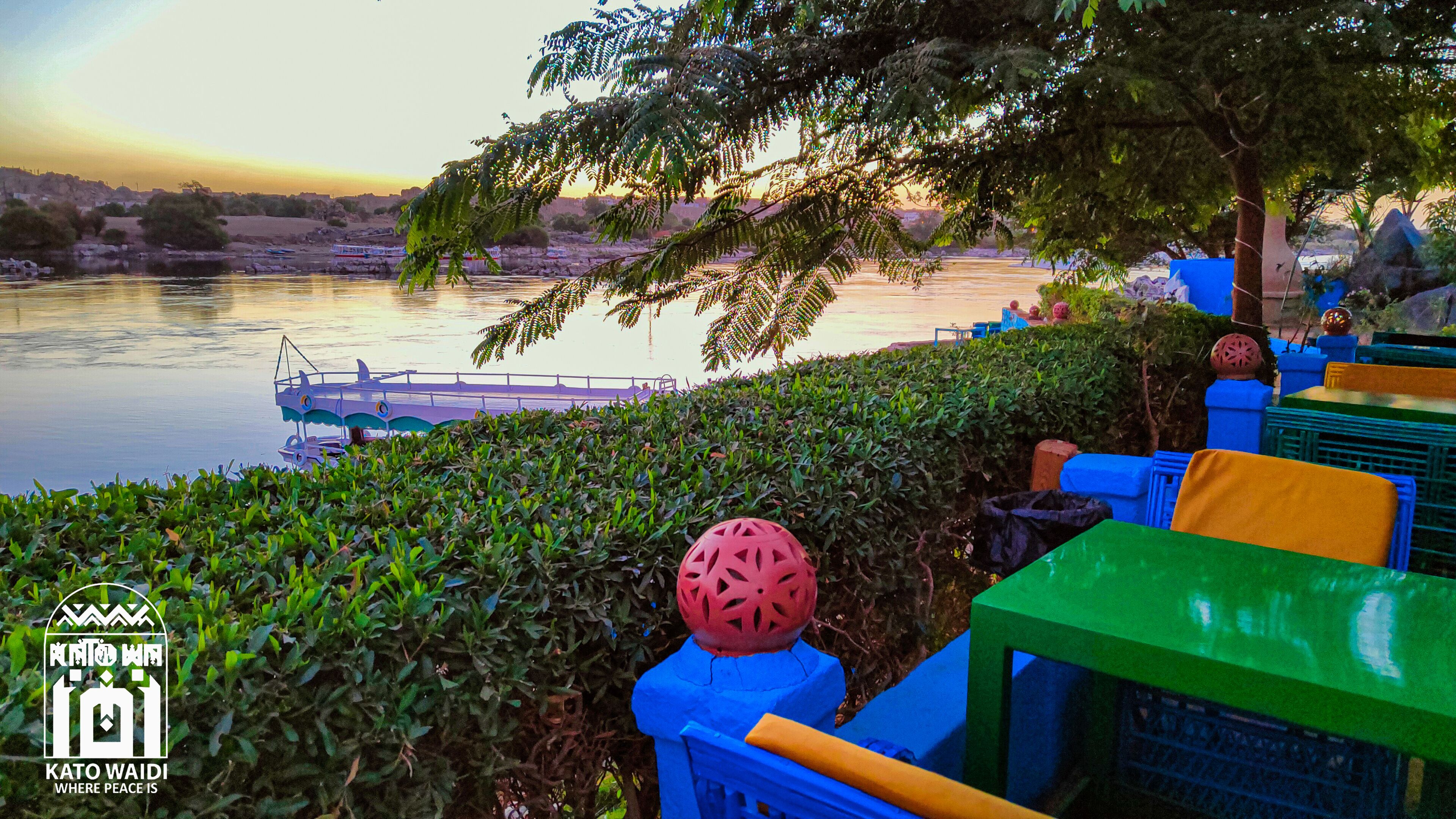 A riverside view with a boat dock, greenery, and seating areas.