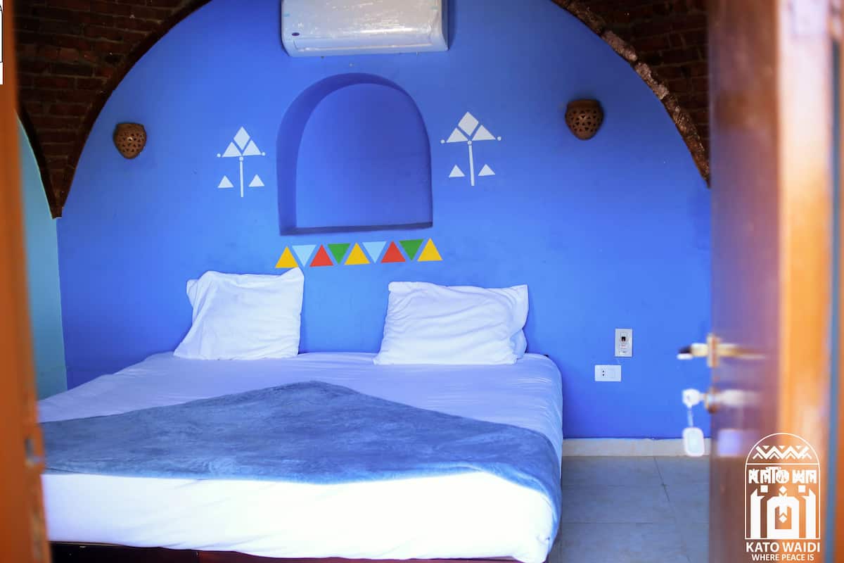 Een kamer met een bed, een blauwe wand en een wit plafond.