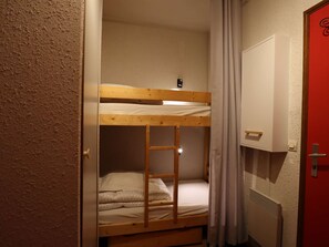 Un letto a castello con una scala, una porta bianca e una parete rossa.