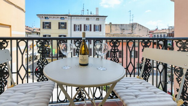 Uma varanda com uma mesa redonda, dois copos de vinho e uma garrafa de vinho Montonale.