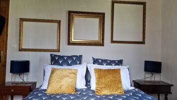 A bedroom with a bed, two nightstands, and three framed mirrors on the wall.