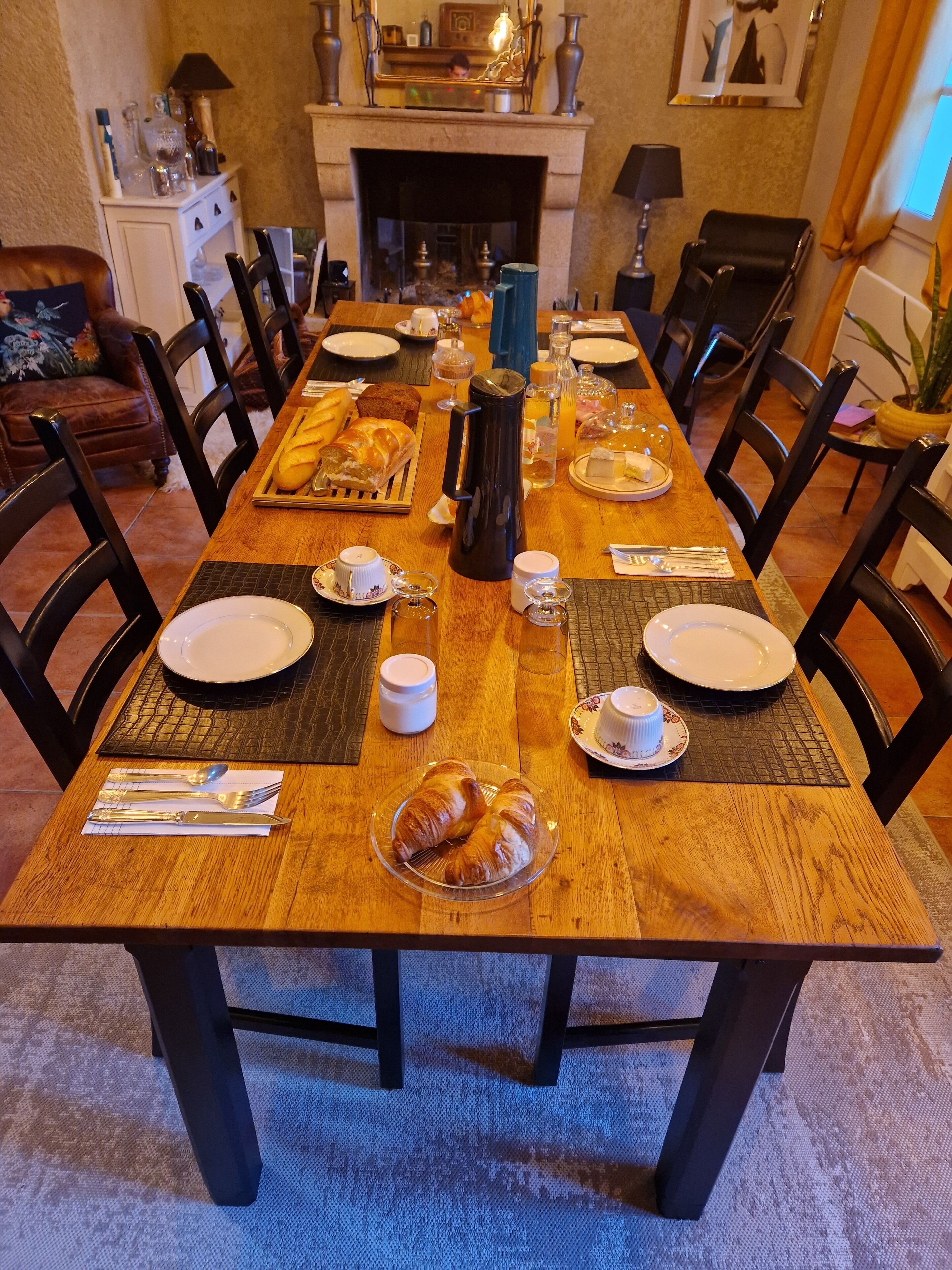 Comedor con una larga mesa de madera dispuesta para una comida, rodeado de sillas.