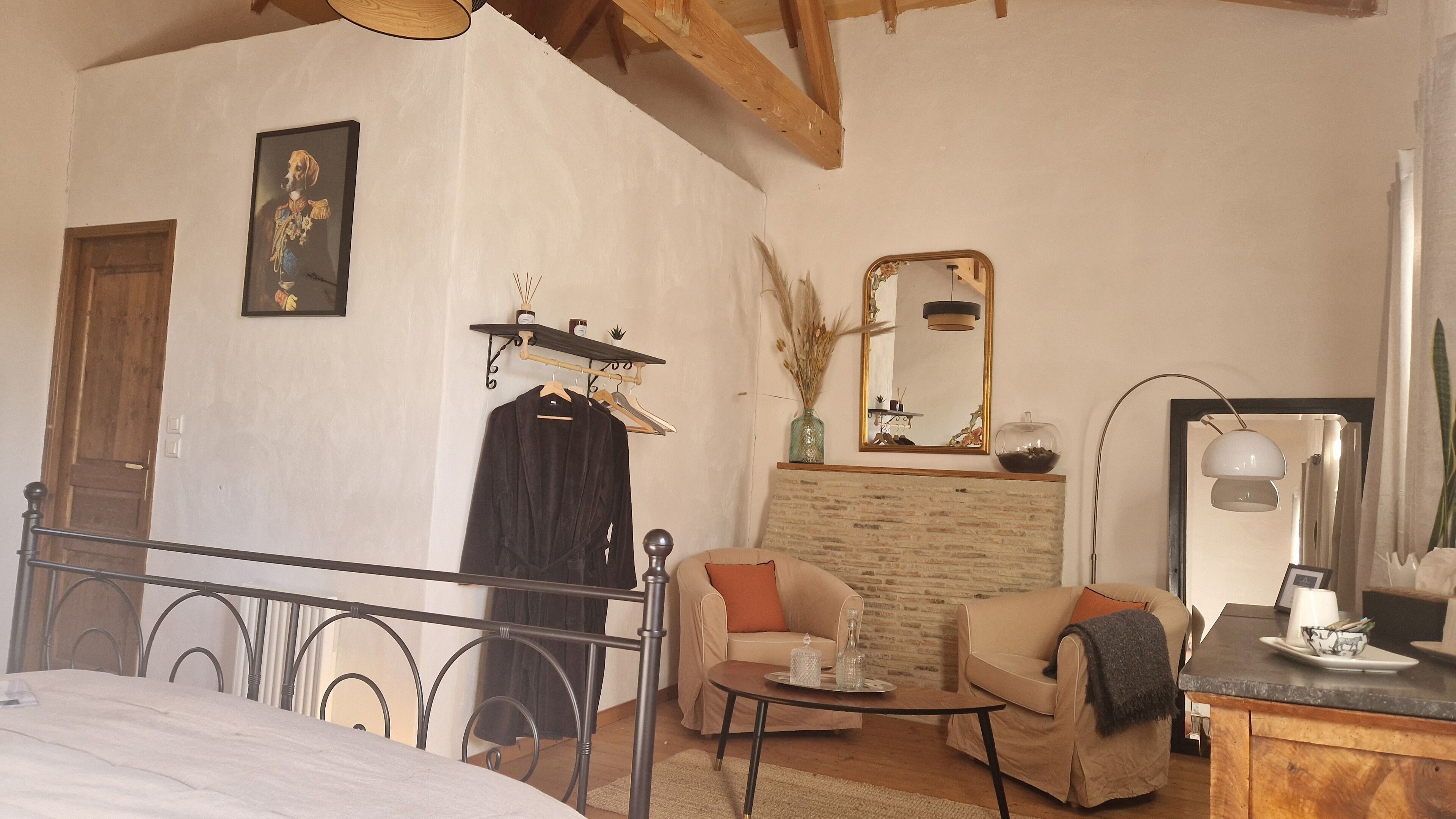 A bedroom with a bed, a chair, a small table, a mirror, and a wardrobe.