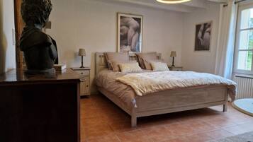 A bedroom with a bed, nightstands, a sculpture, and artwork on the walls.