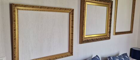 A room with a bed, pillows, a lamp, and three wall-mounted picture frames.