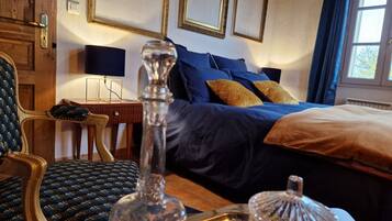 A hotel room with a bed, a chair, a bedside table, and a lamp.