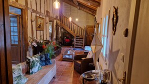 Um interior rústico com vigas de madeira aparente, uma escadaria, uma área de estar com mesa de centro e um aquário.