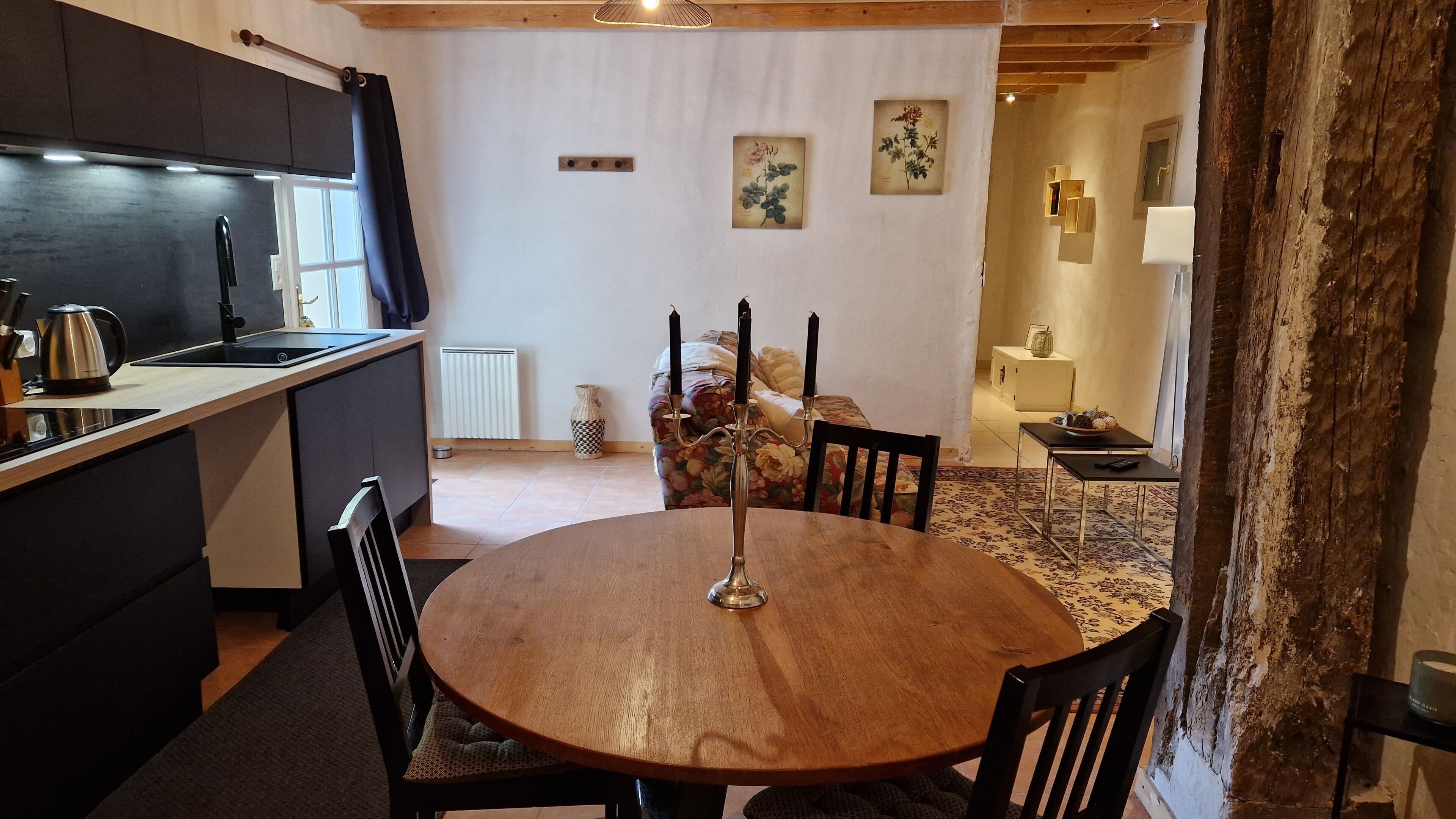 Una cocina acogedora con comedor, que incluye una mesa redonda de madera, sillas negras y un candelabro.