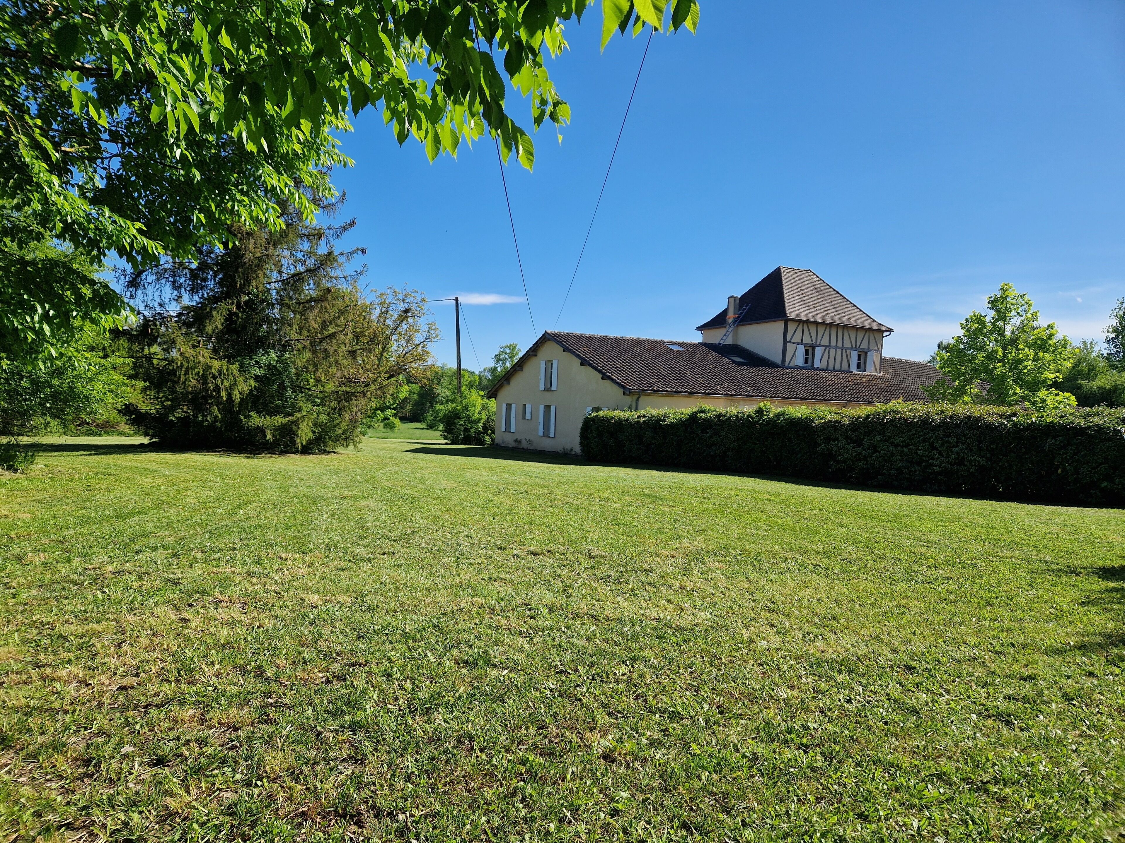 A house with a tiled roof, surrounded by a well-maintained lawn and trees.