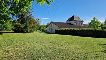 A house with a tiled roof, surrounded by a well-maintained lawn and trees.