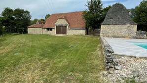 A stone building with a red-tiled roof, a grassy yard, and a swimming pool area. - La Bergerie, oasis of calm for visiting the LOT and the Dordogne (Montgesty)